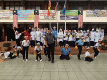 a group of children are posing for a picture in front of a banner that says " hari kemerdekaan malaysia "