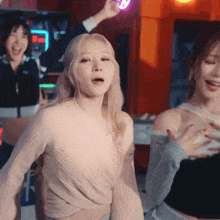 a woman with blonde hair is dancing in front of a neon sign that says exit