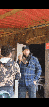 a man in a plaid shirt is holding a bottle in front of a red sign that says attention