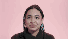 a woman wearing a brown sweater and blue earrings smiles