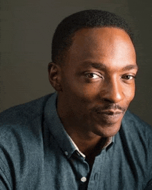 a close up of a man wearing a blue shirt and looking at the camera .