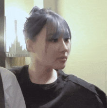a woman with blue hair and a black shirt looks at the camera