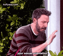a man with a beard is talking about his sexual orientation while standing in front of a building .