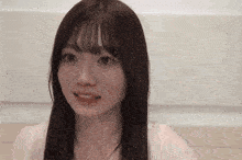 a young woman with long hair and bangs is looking at the camera .