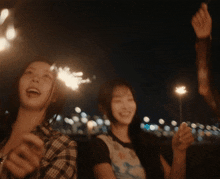 two women holding sparklers in their hands at night