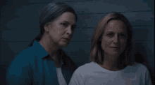 a group of women are standing next to each other in front of a blue brick wall .