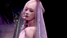 a woman with blonde hair is wearing a white dress and holding a veil over her face .