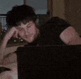 a man in a black shirt is sitting in front of a laptop