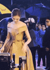 a woman in a gold dress is standing in front of a camera