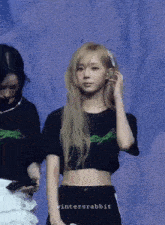 a woman in a black crop top is standing next to another woman in a white skirt with the words wintersrabbit on the bottom