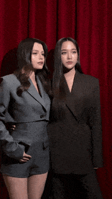two women standing next to each other wearing suits and shorts