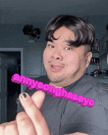 a man with a beard is wearing a black shirt and holding a pink sign that says sunnyeonghaseyo