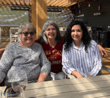 three women are posing for a picture and one of them is wearing a wa state shirt