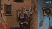 a woman in a purple top is standing in front of a wall with nick written on it