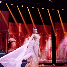 a woman in a long white dress is on a stage