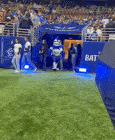 a group of people walking on a football field with a sign that says bat