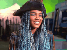 a woman with blue braids and a pirate hat smiles