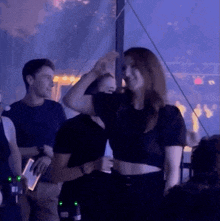 a woman in a black crop top is dancing in a dark room