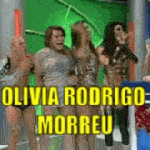 a group of people standing in front of a green screen with olivia rodrigo morreu written in yellow