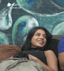 a woman is laying on a couch with a man and smiling .