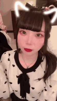 a girl with cat ears on her head is wearing a sweater with hearts on it