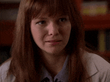 a woman with red hair is wearing a lab coat