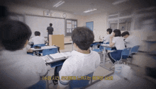 a group of students are sitting at desks in a classroom with a man standing in front of a whiteboard that says korea