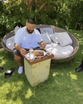 a man is sitting on a couch with a tray of food on it .