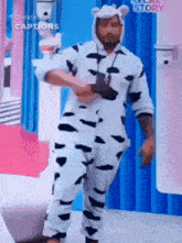 a man in a cow costume is dancing in front of a blue wall .