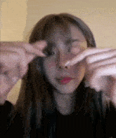 a close up of a woman 's face with her hands covering her eyes .