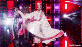 a woman in a long white dress is dancing on a stage ..
