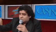 a man holding a microphone in front of a sign that says casino