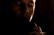 a man is smoking a cigarette in a dark room .