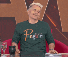 two men are sitting on a red couch and one has a lask sweatshirt on