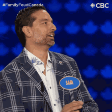 a man wearing a plaid jacket has a name tag that says sam