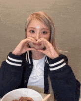 a girl making a heart shape with her hands over her mouth