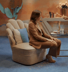a woman sits in a chair with a blue pillow on it