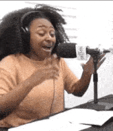 a woman wearing headphones is singing into a microphone in a studio .