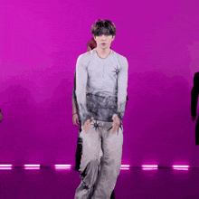 a man in a white shirt and grey pants is dancing on a purple background .