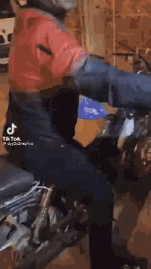 a man in a red shirt is riding a motorcycle in a tiktok video .