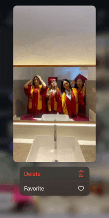 a phone screen shows a picture of a group of graduates and says delete