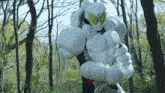 a statue of a robot in a forest with trees in the background and a blue sky