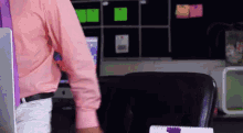 a man in a pink shirt and purple tie stands in front of a desk with a calendar on it