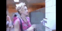 a woman in a pink shirt is standing in front of a sink in a bathroom .