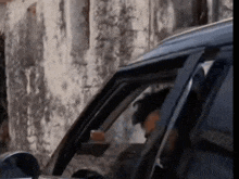 a man is sitting in a black car looking out the window .