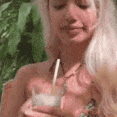 a woman in a bikini is drinking through a straw from a glass .