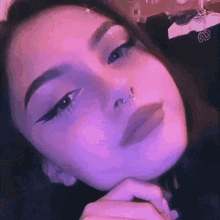 a close up of a woman 's face with a nose ring on it .