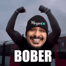 a man wearing a beanie that says blizzard flexes his arms