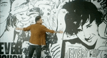 a man is standing in front of a wall with drawings and the word " every " on it