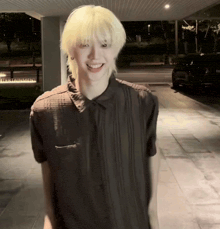 a man with blonde hair wearing a black shirt smiles